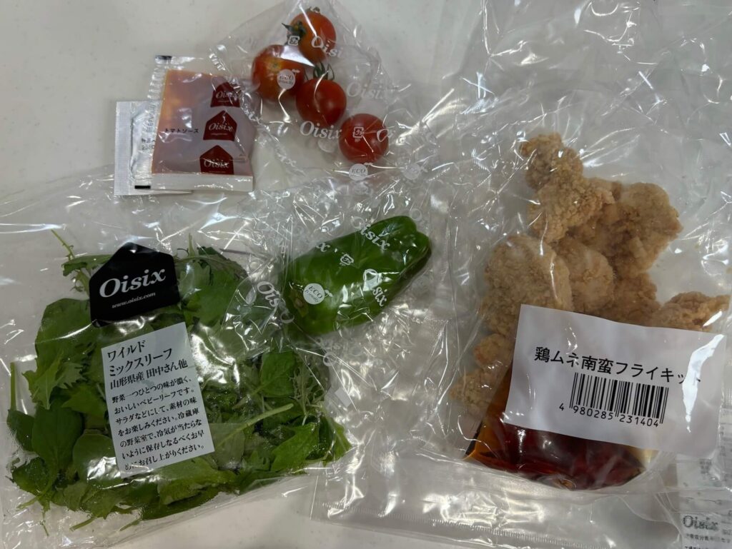 kit oisixチキンサルサが届いた状態でミニトマト、ピーマン、ワイルドミックスベリー、鶏むね肉フライキットが写っている。